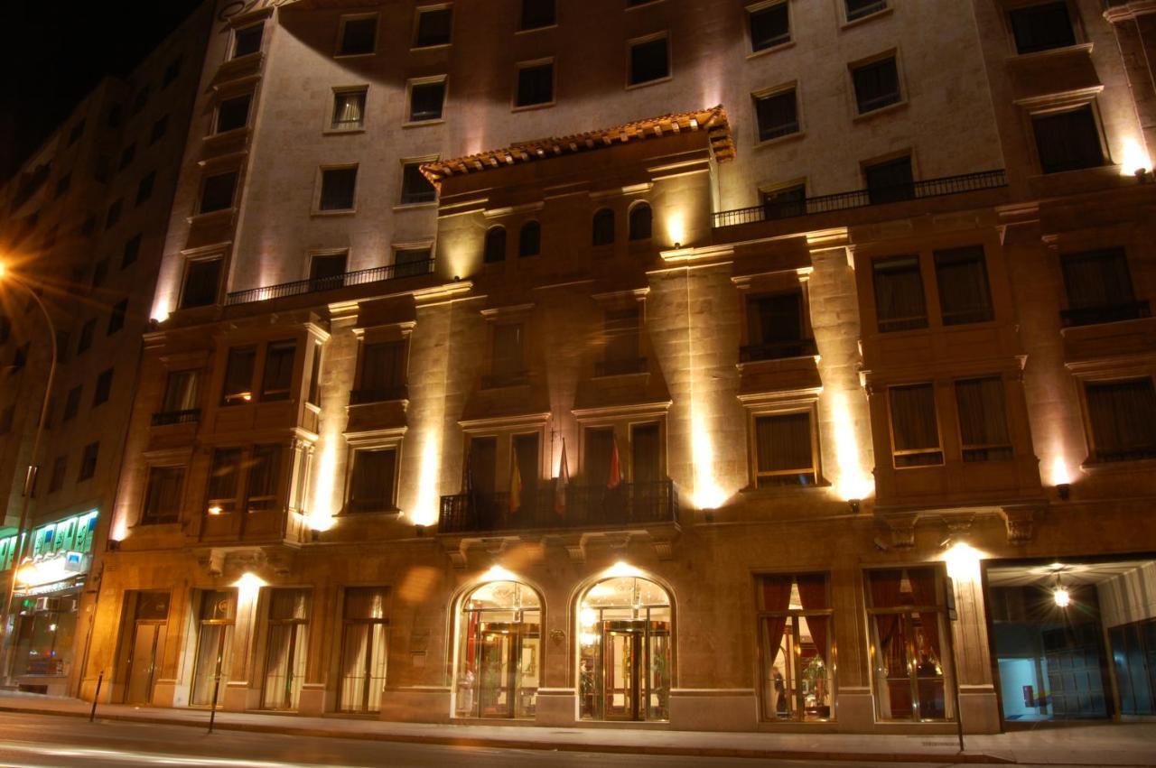 Hotel Alameda Palace Salamanca Kültér fotó The photo shows the exterior of a building, likely a hotel, illuminated at night. The facade features a combination of decorative architectural elements, including a prominent entrance framed by large windows. Soft lighting highlights the building's 