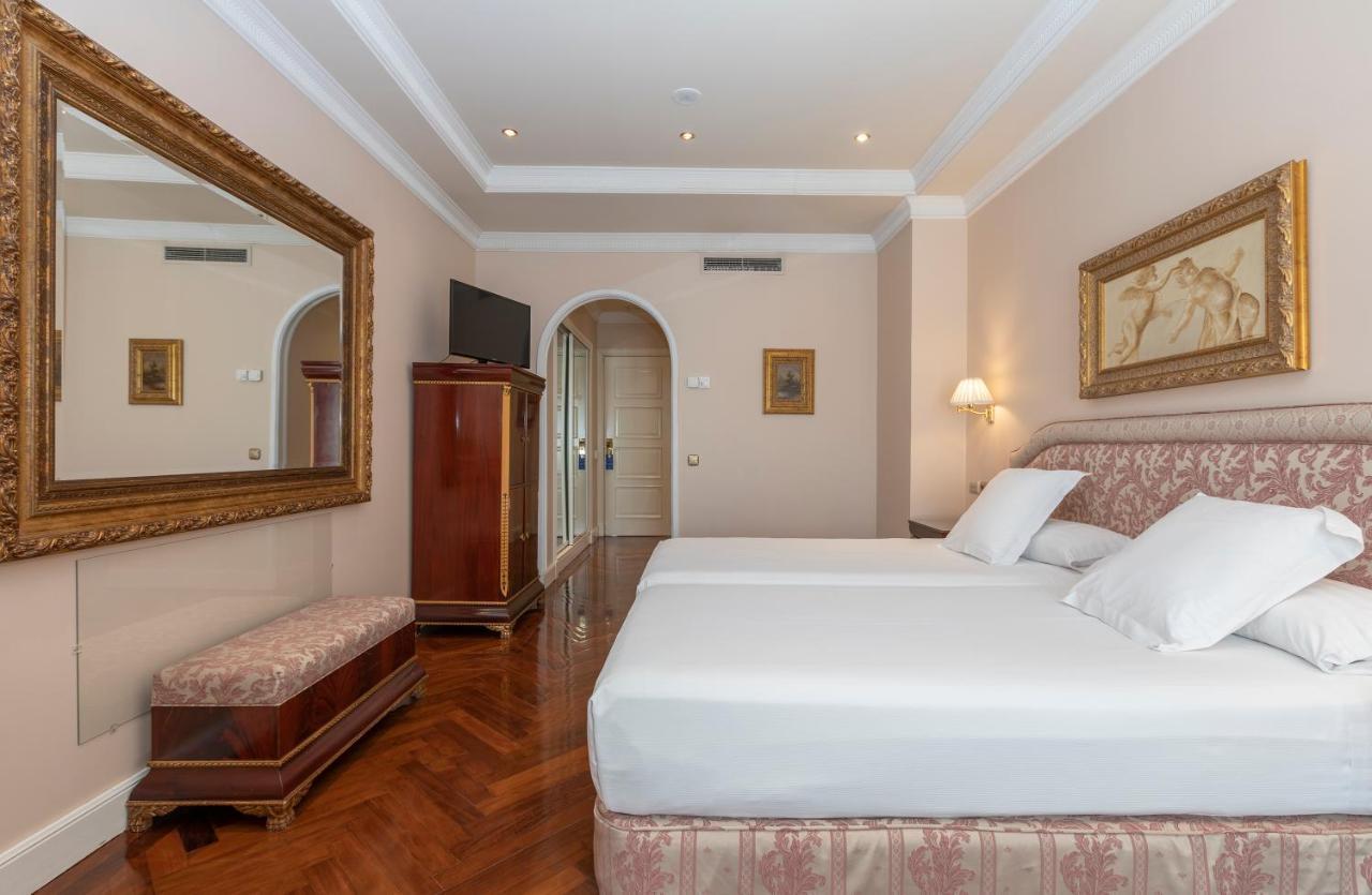 Hotel Alameda Palace Salamanca Kültér fotó The image shows a well-decorated hotel room featuring two twin beds with white bedding and decorative pillows. There's a large mirror on the wall, reflecting the room's elegant design. A wooden wardrobe is positioned next to the bed, and a small benc