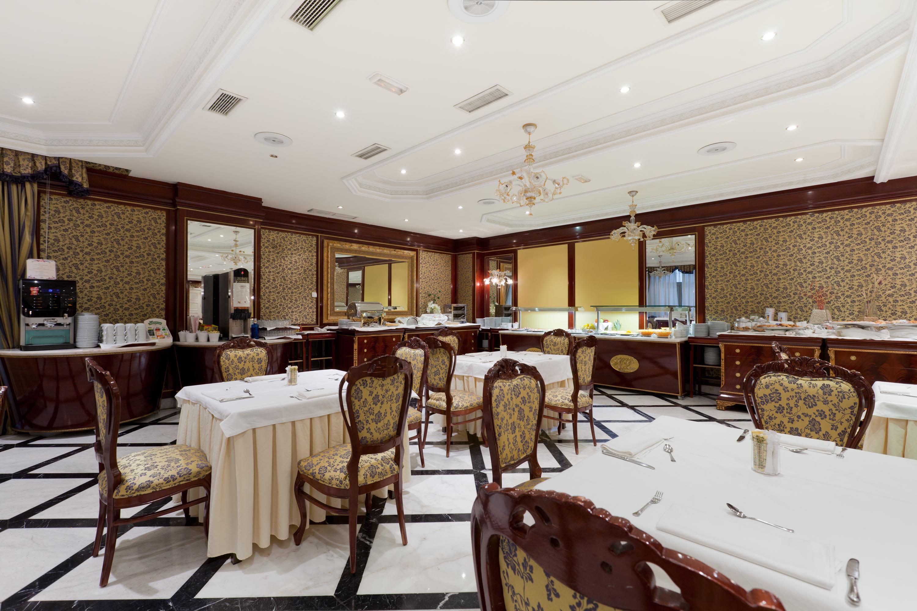 Hotel Alameda Palace Salamanca Kültér fotó The photo depicts an elegant dining room in a restaurant. The interior features ornate decorations, including patterned wallpaper and a sophisticated chandelier hanging from the ceiling. There are several well-arranged tables, each with white tablecl