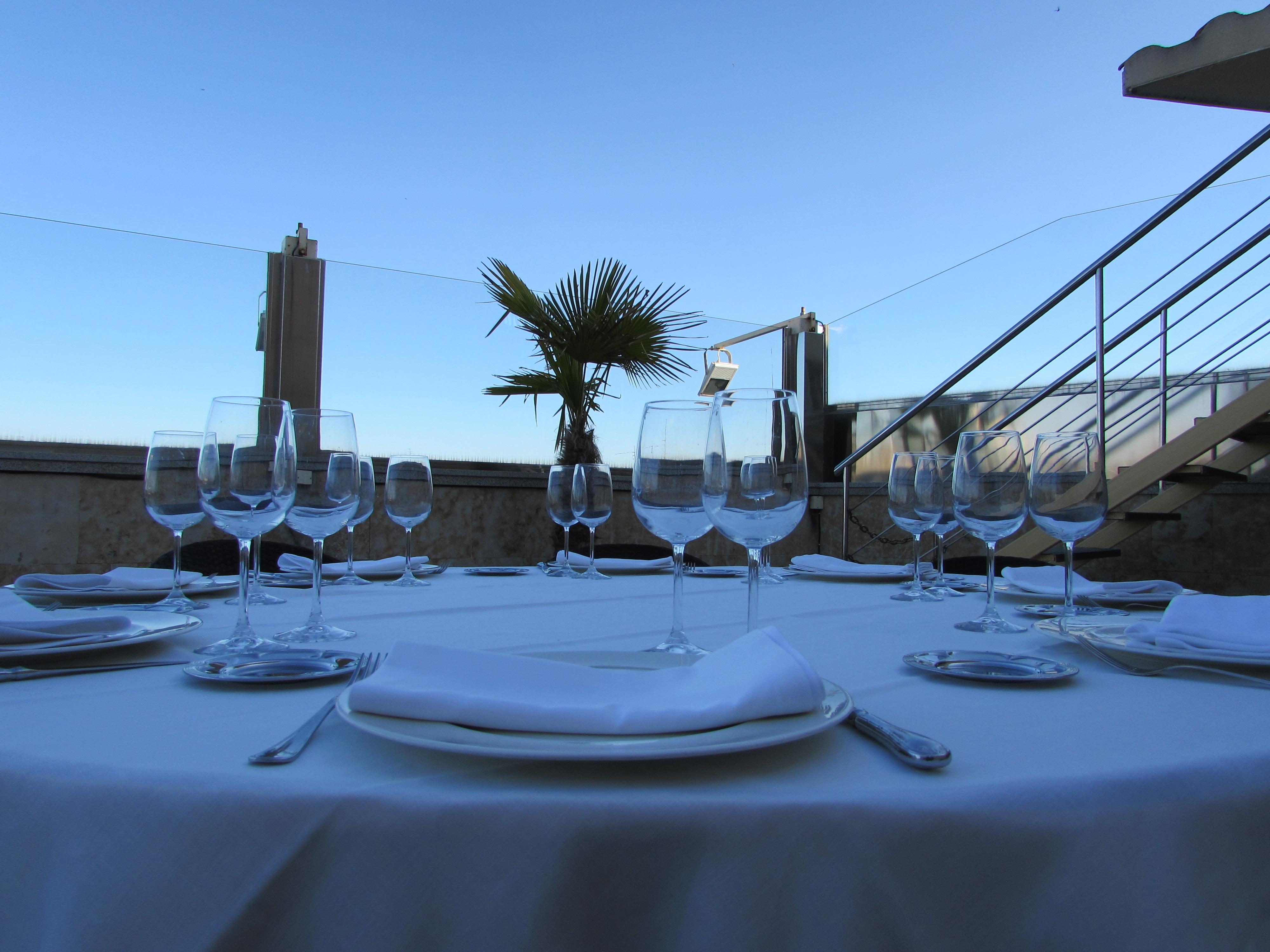 Hotel Alameda Palace Salamanca Kültér fotó The photo depicts a beautifully set dining table outdoors. The table is covered with a white tablecloth and features several glassware pieces arranged with precision. There are multiple wine glasses and stemware, along with plates and silverware posi