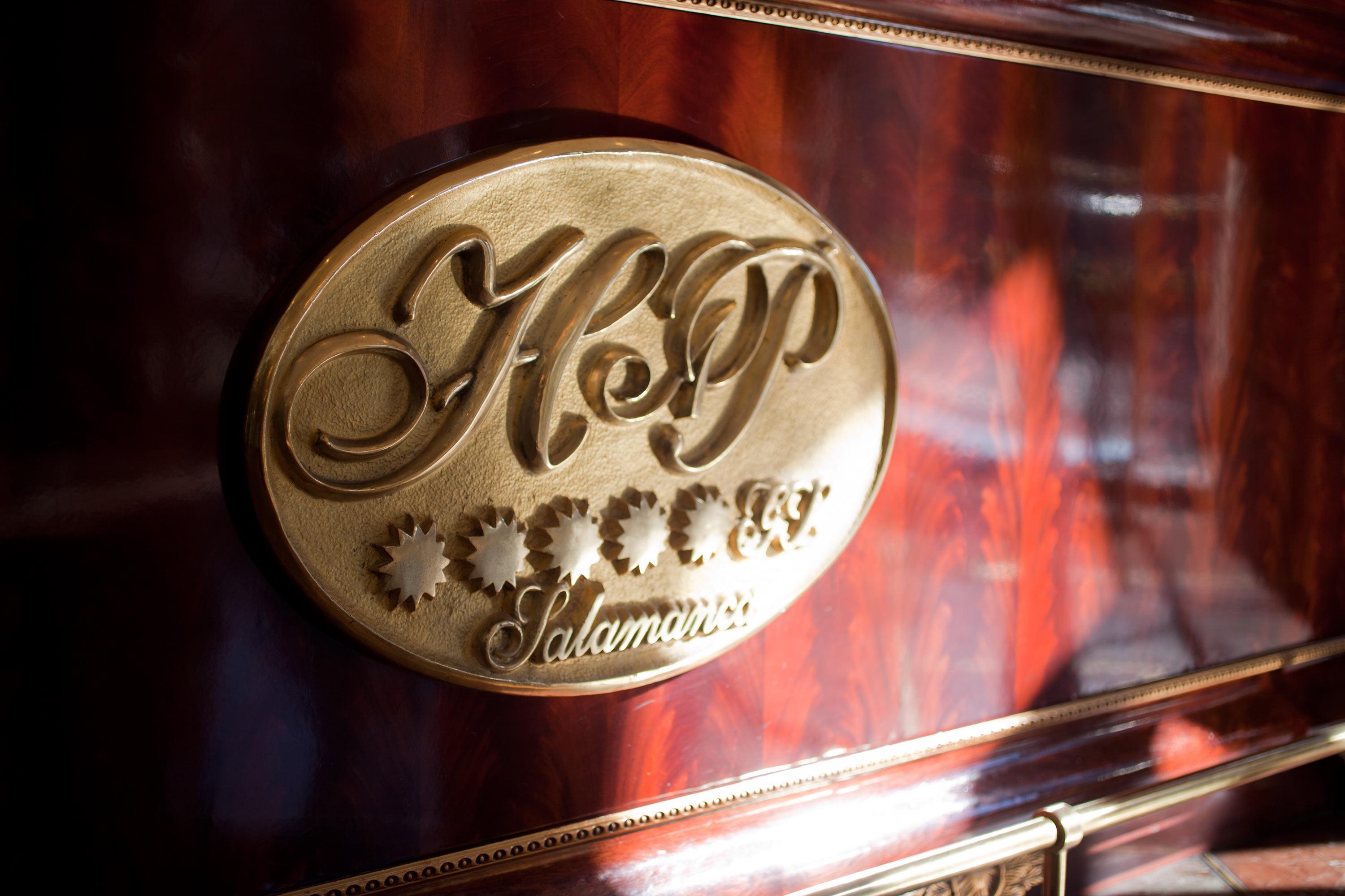 Hotel Alameda Palace Salamanca Kültér fotó The photo shows a decorative emblem with the letters "H&P" in an elegant script. The emblem appears to be made of gold or a gold-tone material and is set against a rich wooden surface, suggesting a luxurious or high-quality item. Below the letters, t