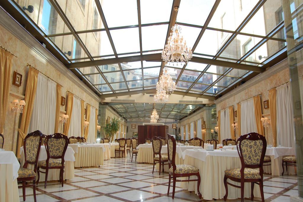 Hotel Alameda Palace Salamanca Kültér fotó The photo shows an elegant dining area in a restaurant. The space features a glass ceiling that allows natural light to fill the room, enhancing its bright and airy atmosphere. The flooring is tiled in a classic pattern, and the tables are elegantly 